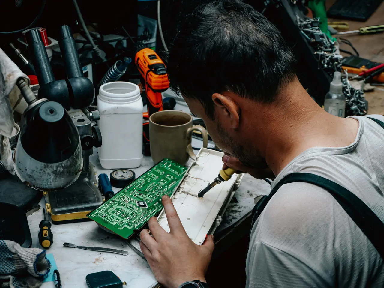 Technician carrying out printed circuit board rework at an electronics bench
